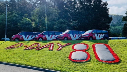 A poppy display at our Llandudno Centre spelling out "D Day 80" with four Blind Veterans UK vehicles behind it