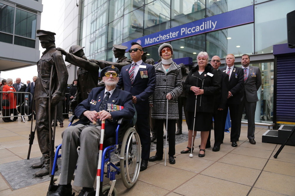 Seven blind veterans next to our Victory Over Blindness statue outside Manchester Piccadilly station