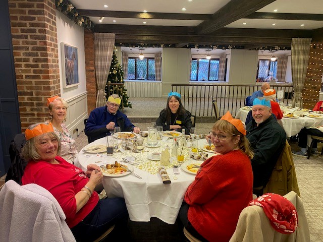 A group of veterans and staff sit around a table and pose for a photo
