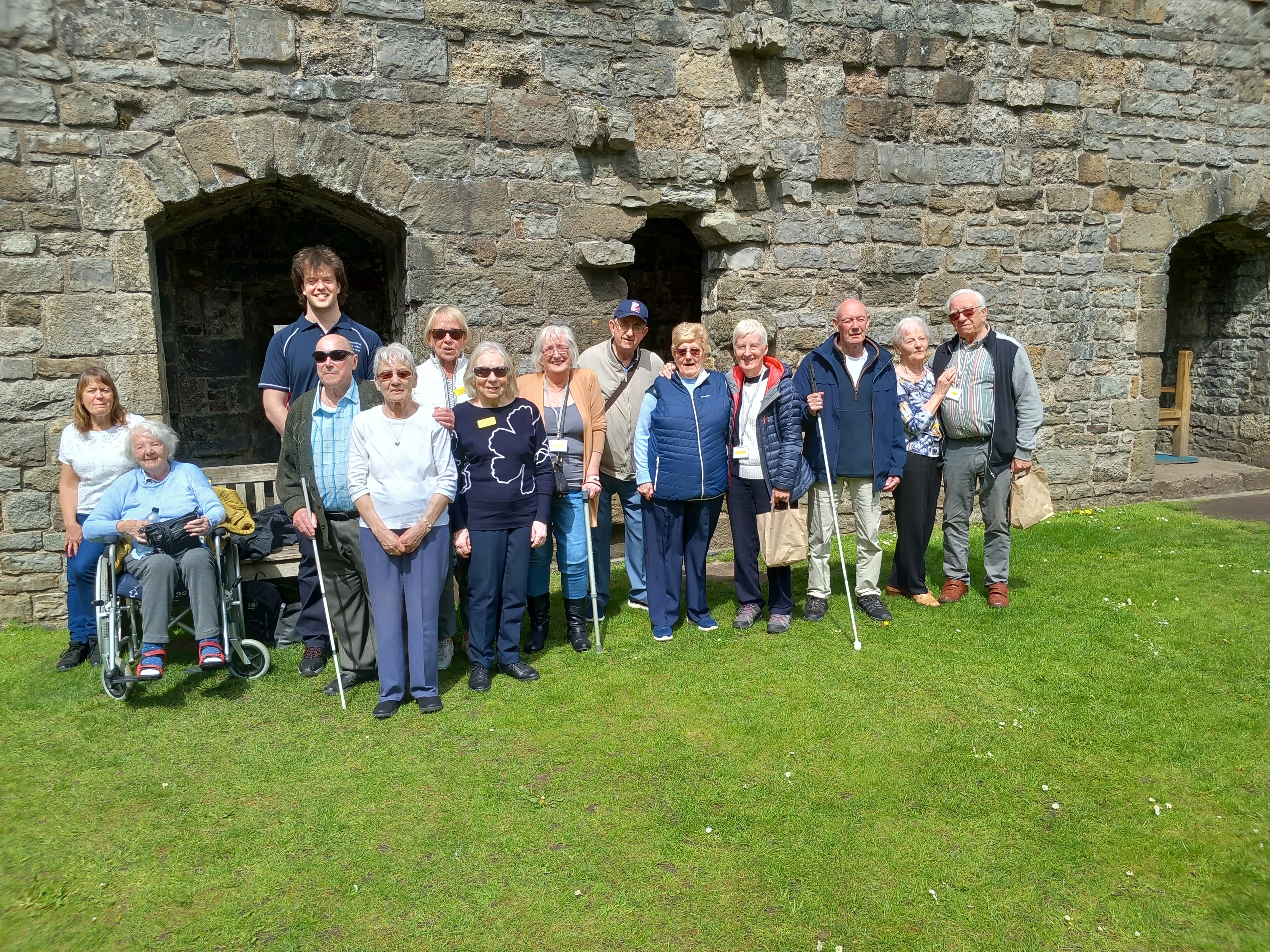 A group of blind veterans posing for a photograph in front of a castle wall