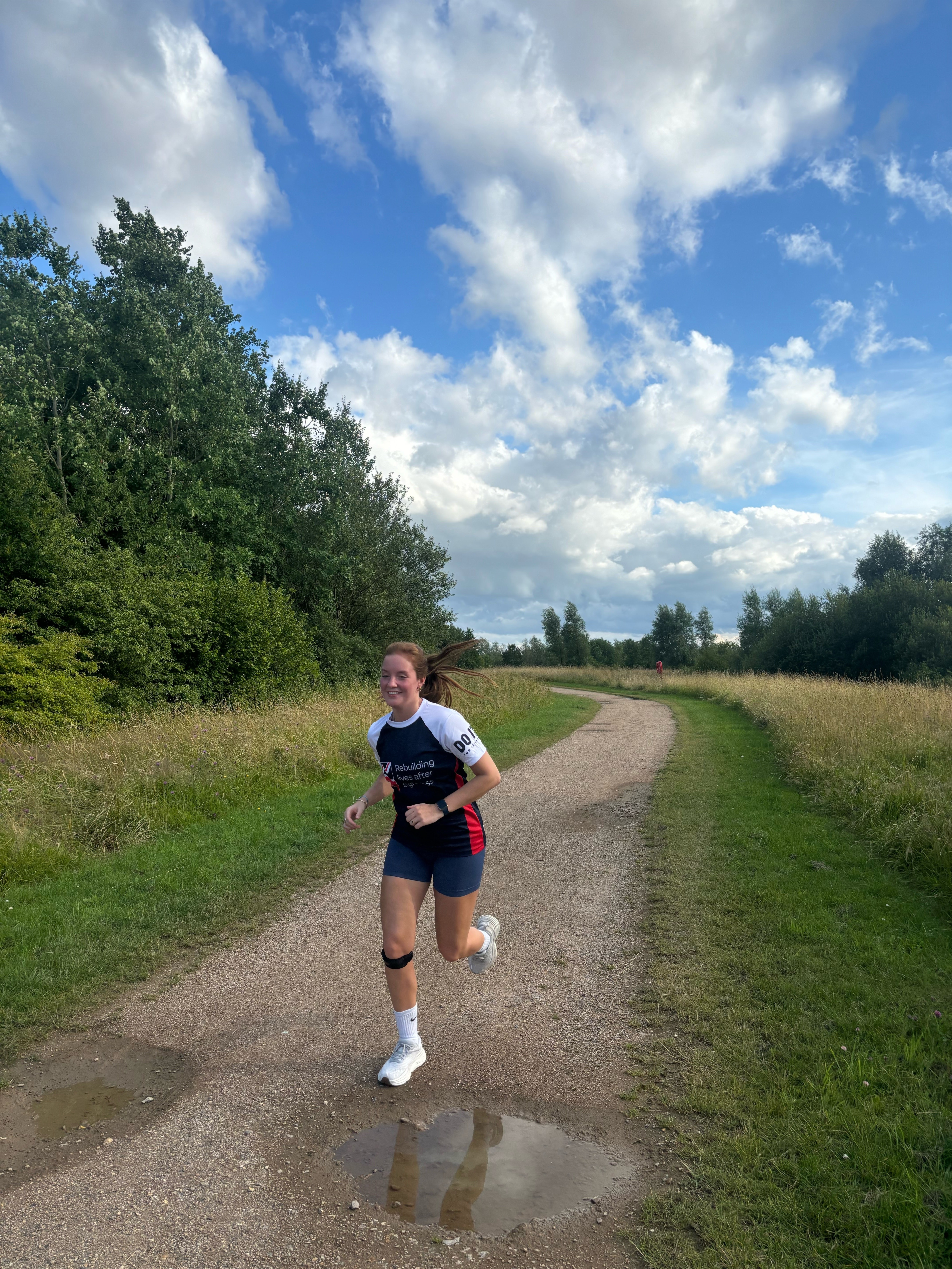 Grace is running along a gravel path wearing her Blind Veterans UK t-shirt