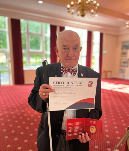 Blind Veterans Bob stood holding his white cane and Founders Day certificate
