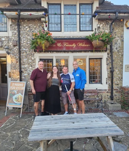 Group of four, including Stu in his Blind Veterans UK t-shirt, are stood outside the front of Ye Olde House at Home to pose for a picture