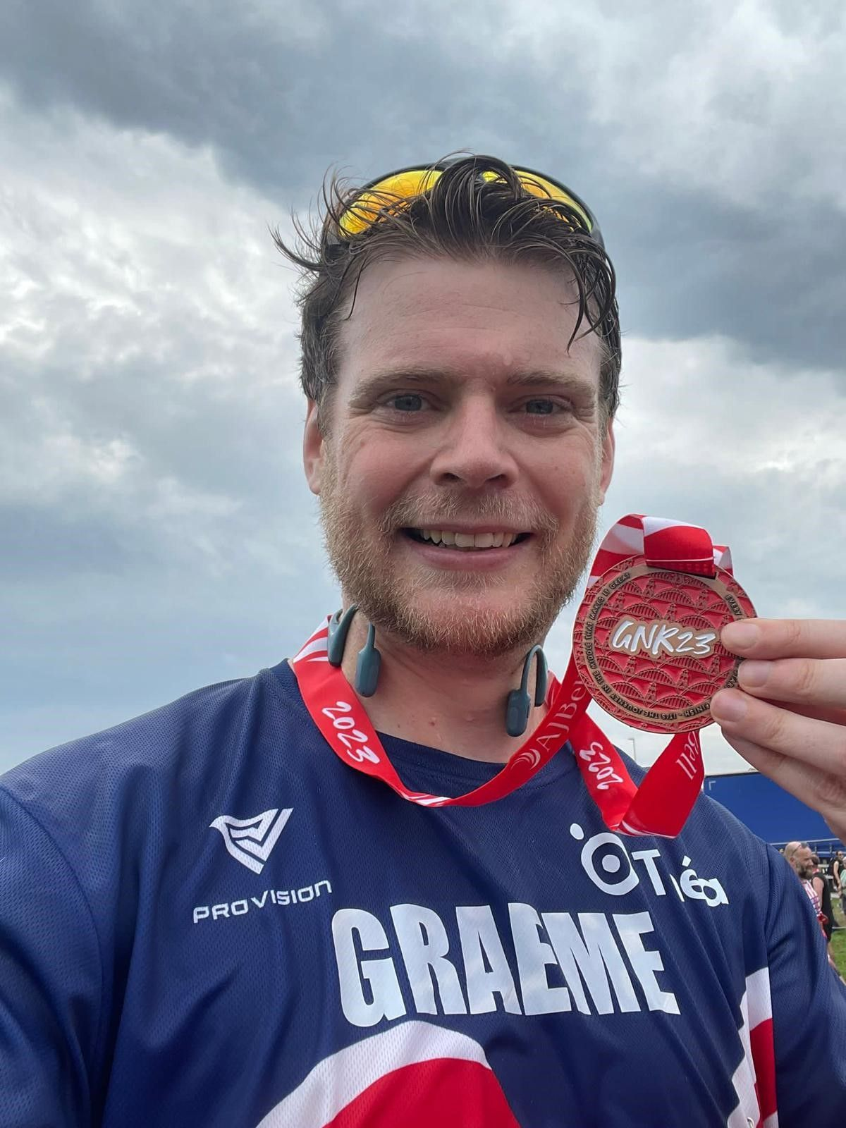 A flushed but happy looking Graeme holds his medal up as he smiles for the camera.