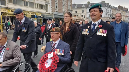 Anthony is pushed in his wheelchair as he makes his way through Llandudno proudly holding a wreath and displaying his medals