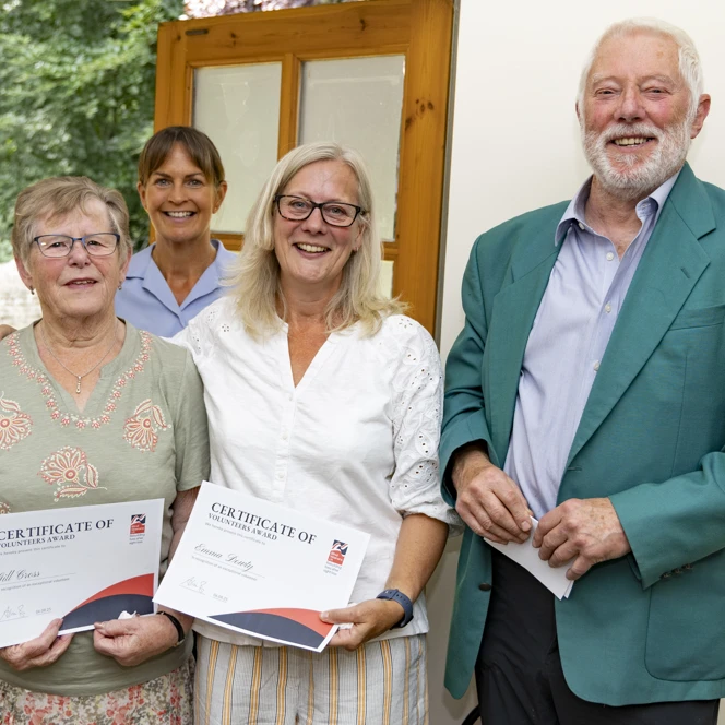 Four people standing together smiling after the Founders Awards ceremony at RAF Carnwell. Volunteers Gill and Emma are holding their certificates, joined by Warrant Officer Tracey, and Russel Hibbins, who nominated them.