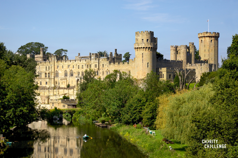 The imposing Warwick Castle towering alongside the tree lined banks of the River Avon.