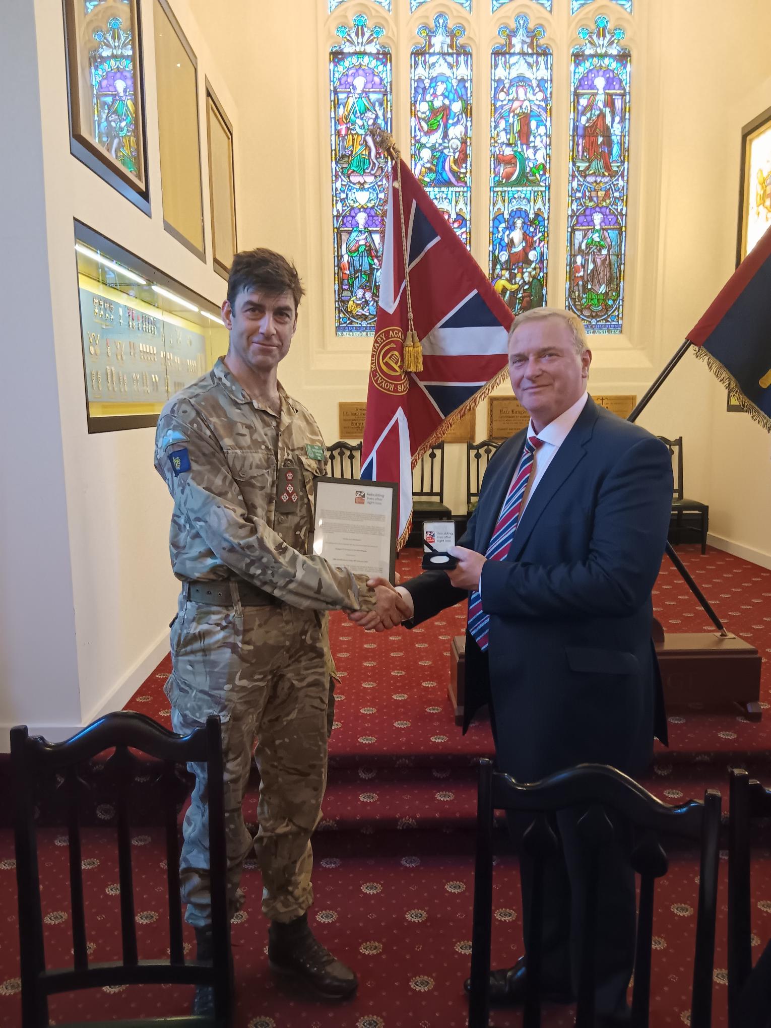 rigadier N M Wight-Boycott OBE presented with a coin in thanks for hosting a dinner at Sandhurst Military Academy.