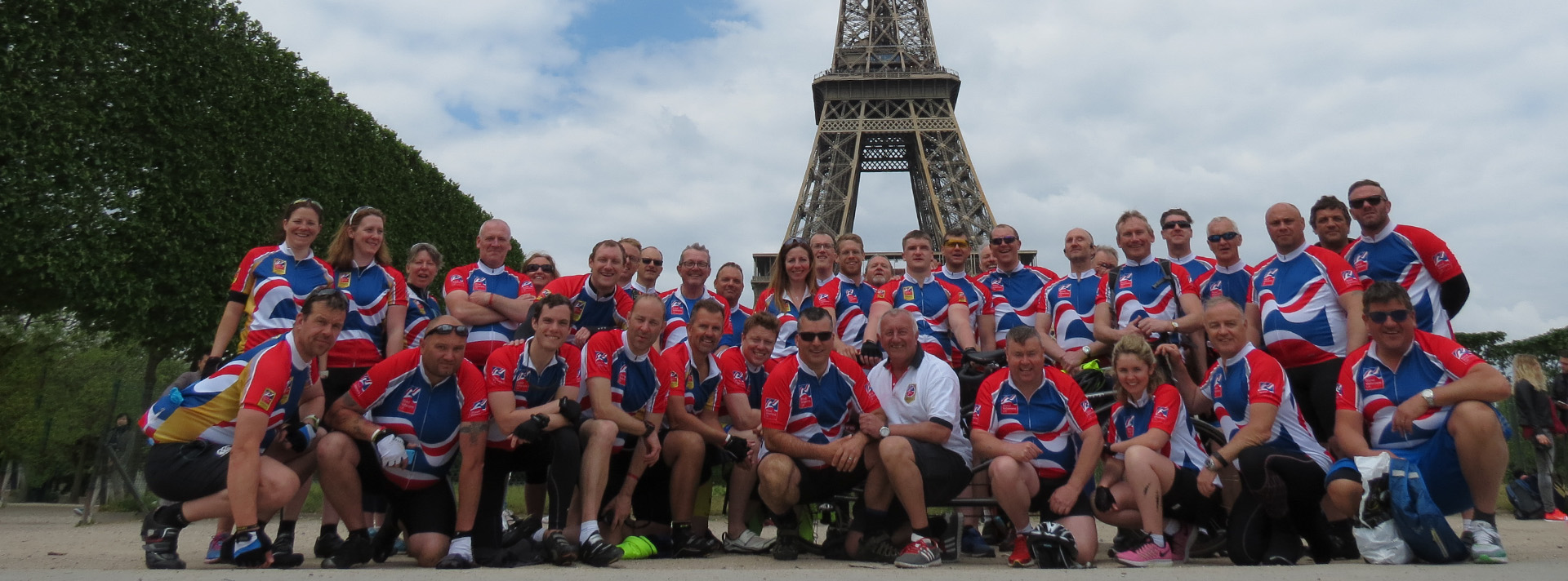A  large group of blind veterans and charity supporters wearing Blind Veteran UK cycling vests as they pose in front of the Eiffel Tower