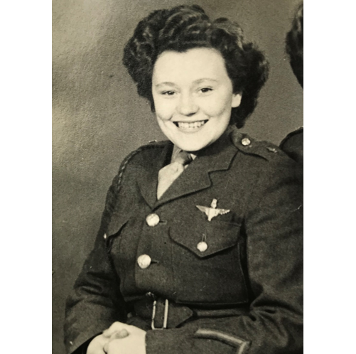 A black and white portrait of Neena during her military service, smiling in military uniform.