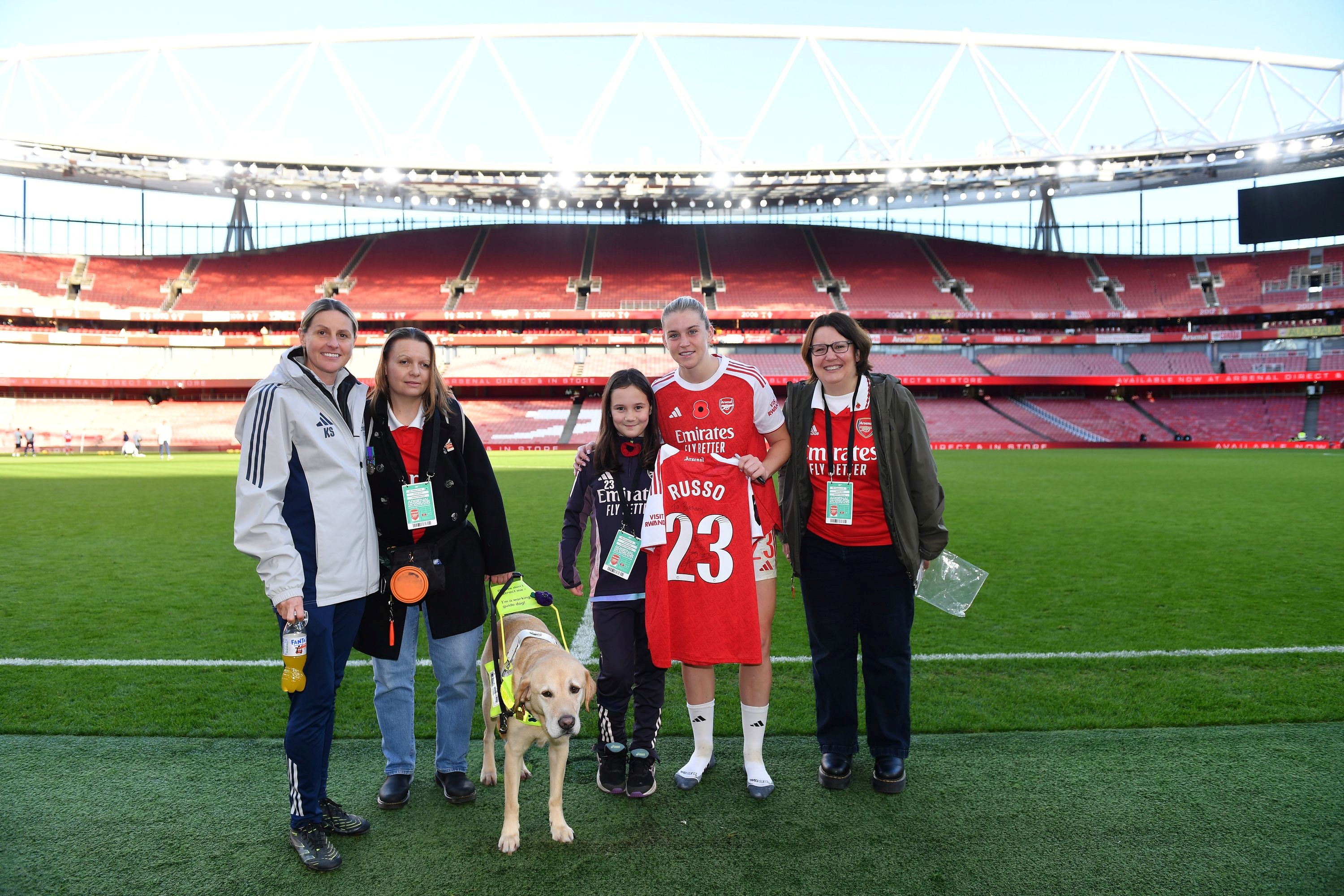 Blind veteran Kelly and guide dog Archie are stood next to footballer Kelly Smith who has her arm around Kelly. Footballer Alessia Russo is stood between Bethany and Sarah.