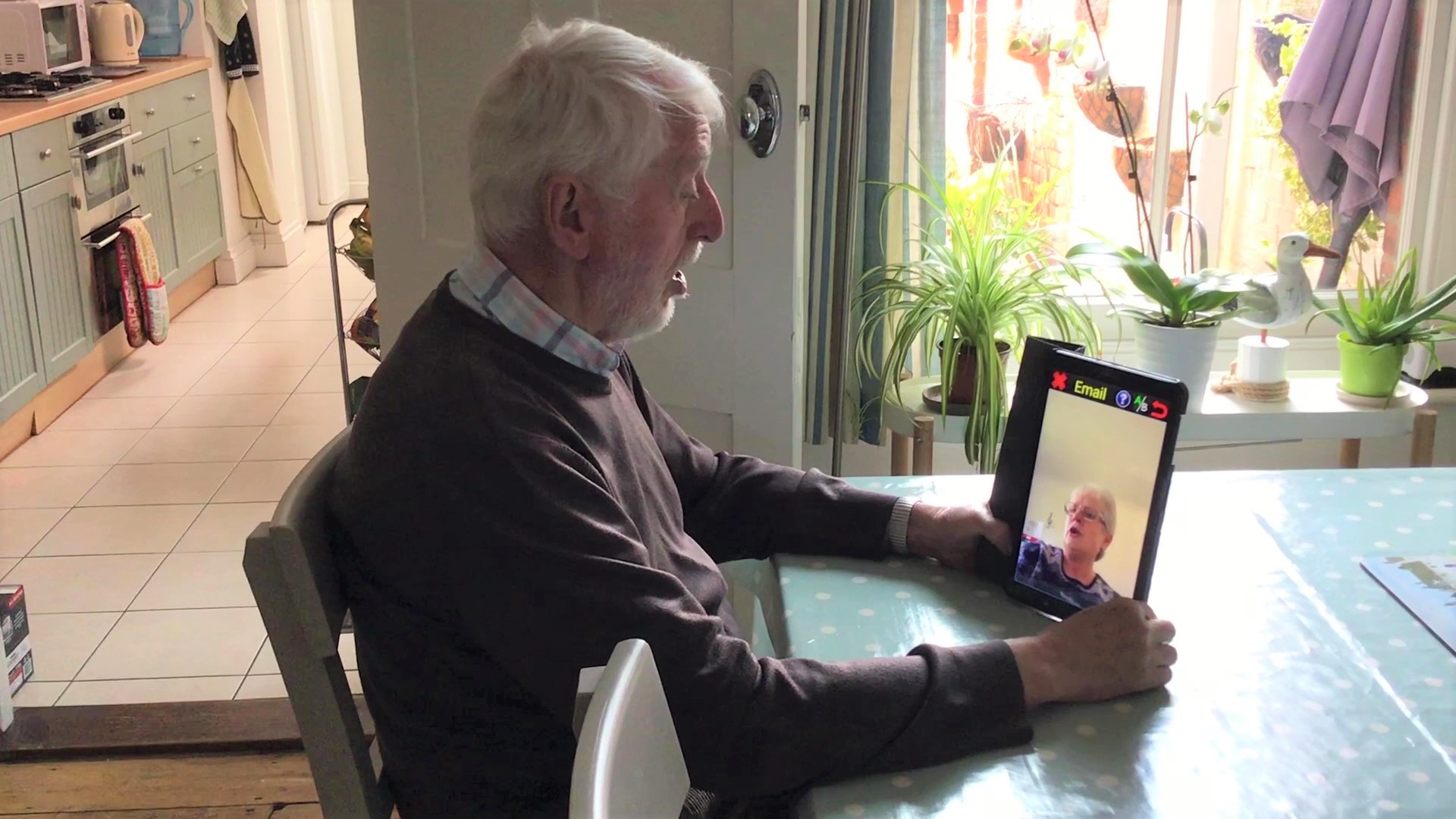 Blind veteran Colin sitting at desk in front of a tablet practicing singing while on Zoom call