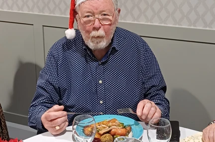 Mike is wearing a Christmas hat and eating a Christmas dinner
