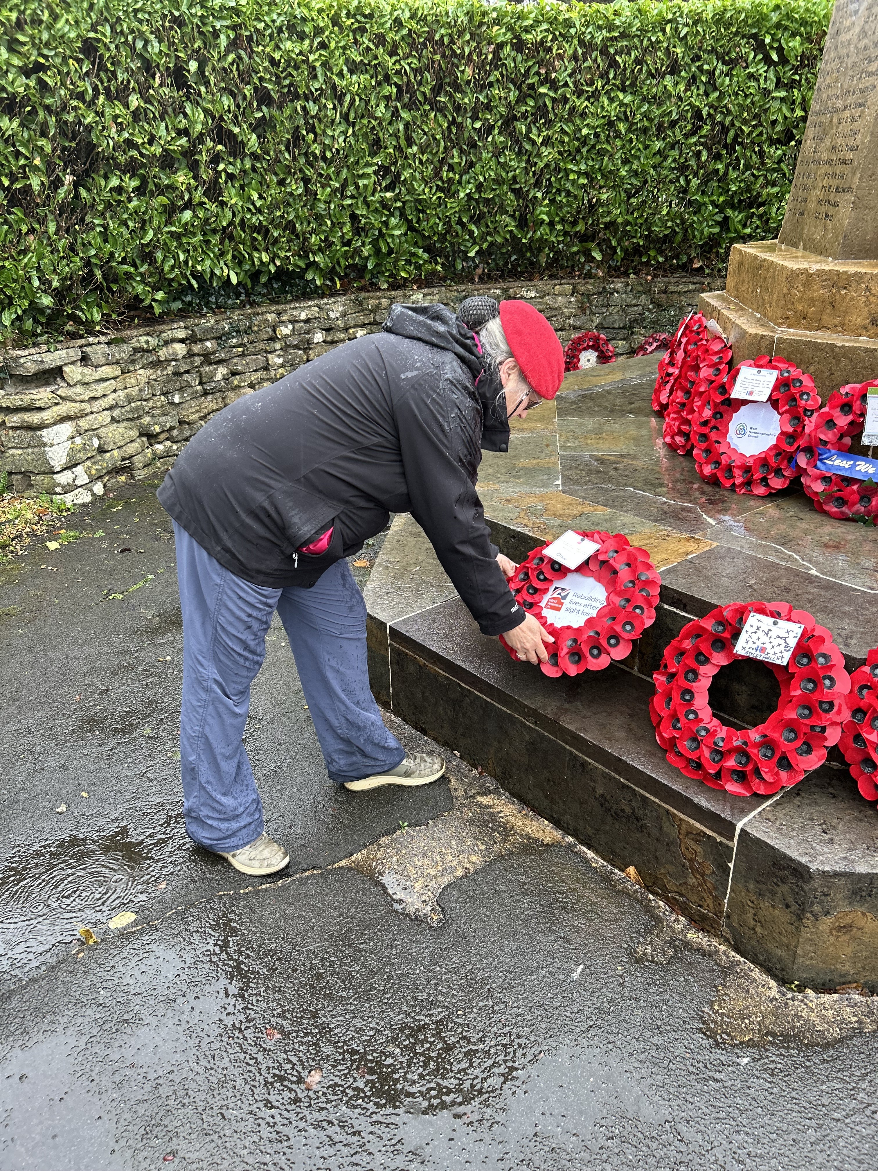 Jennie is bent forwards carefully placing her wreath at the war memorial in Daventry