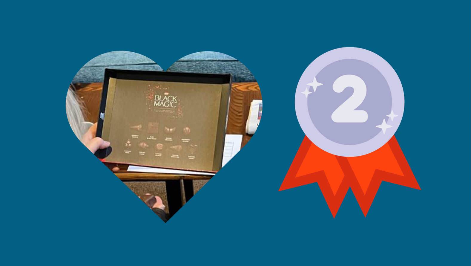 A box of Black Magic chocolates, visible in a heart shaped cut-out, against a teal background. Beside the heart is a graphic of a silver medal with a number 2, indicating second place.