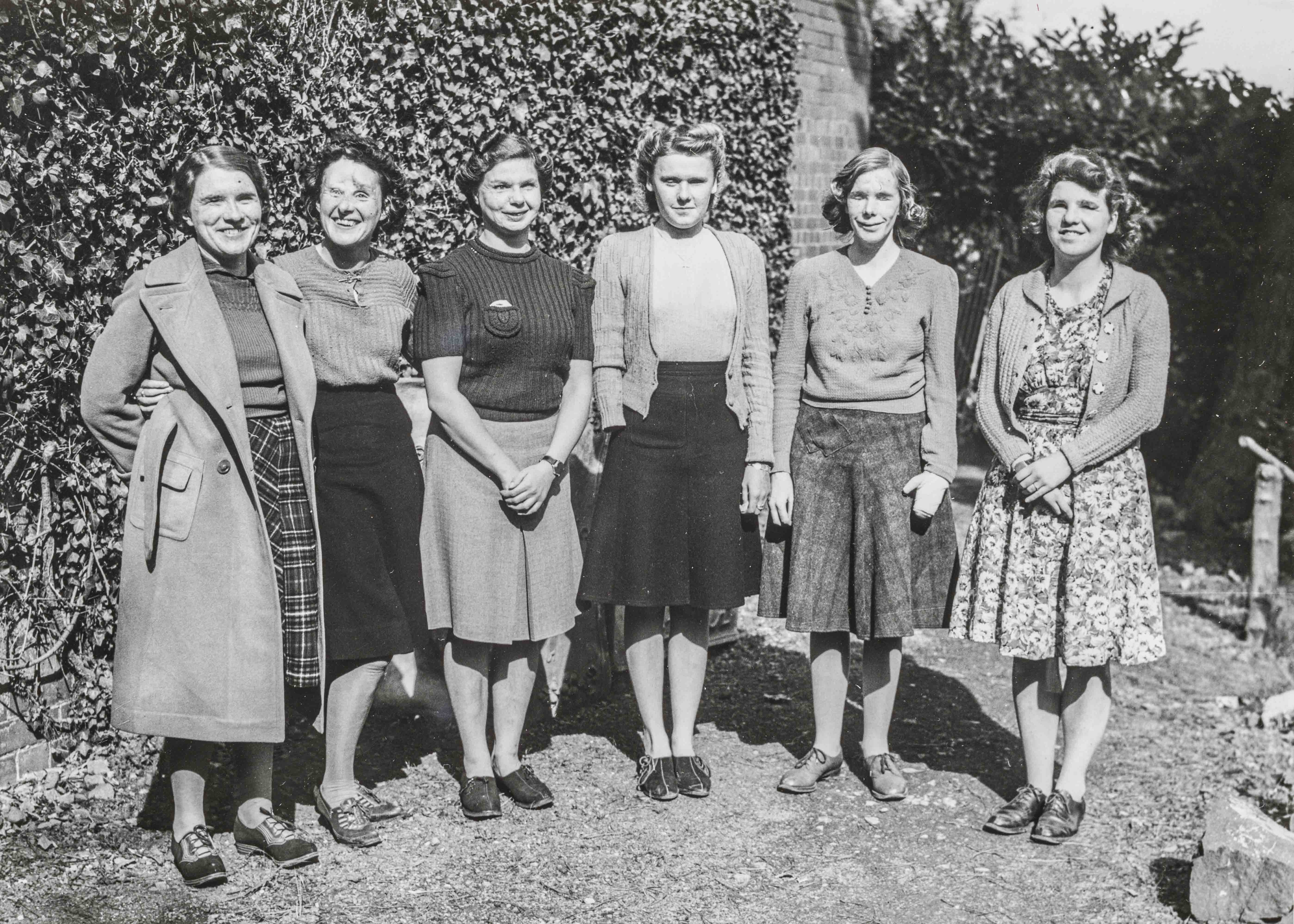 An archive photograph of a blind veteran Barbara standing outside smiling with a group of female blind veterans
