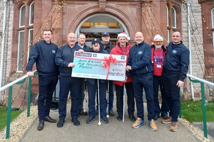 A group of people stand in front of the Llandudno centre holding a large cheque