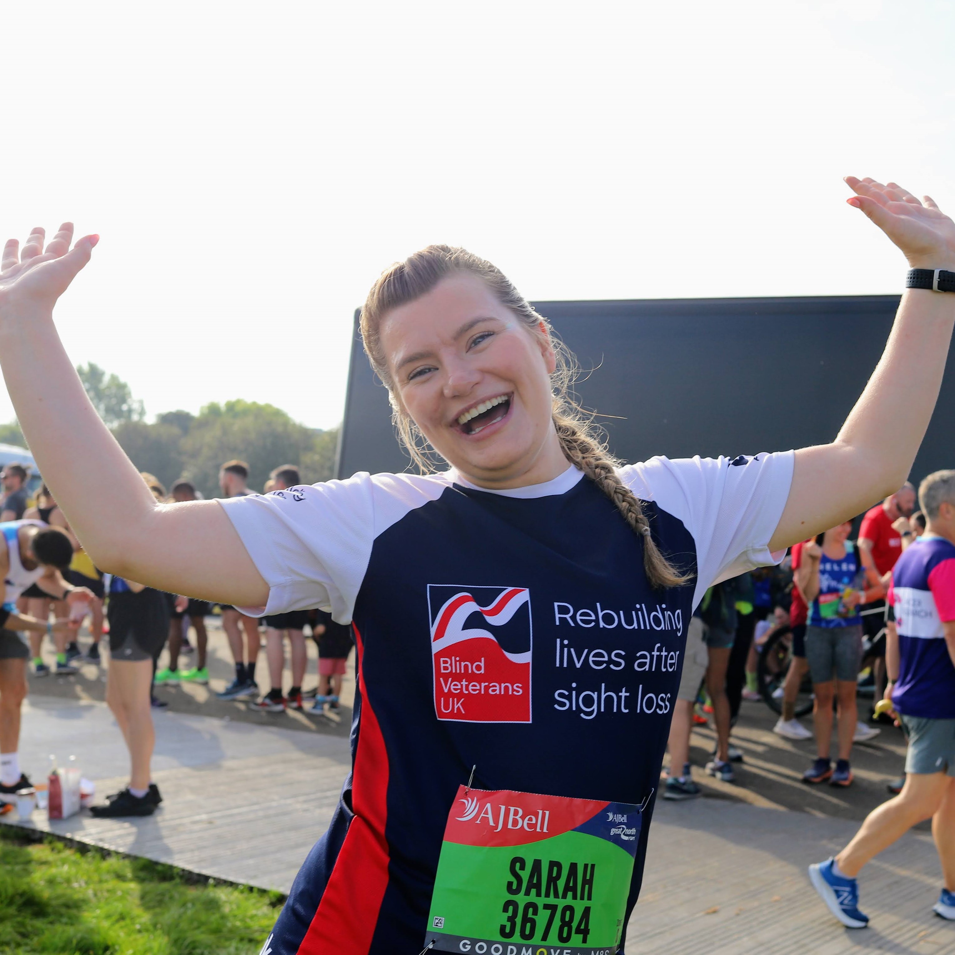 A beaming Sarah in her Blind Veterans UK sports top, waving her arms in the air.