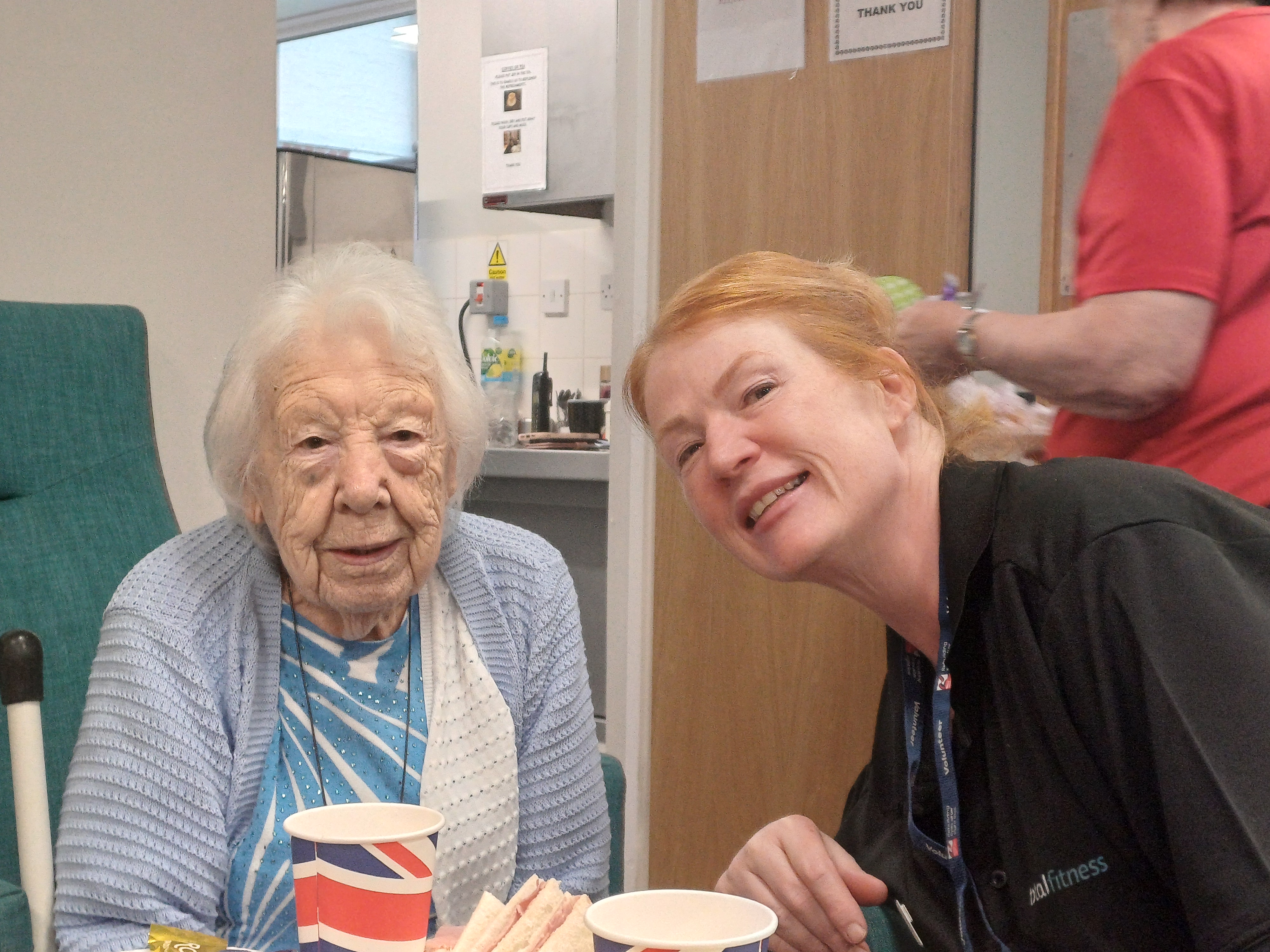 Blind veteran Olly and volunteer Lanie smiling together inside.