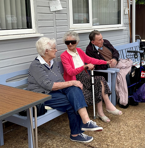 Three veterans sitting on a bench spectating at the bowls event
