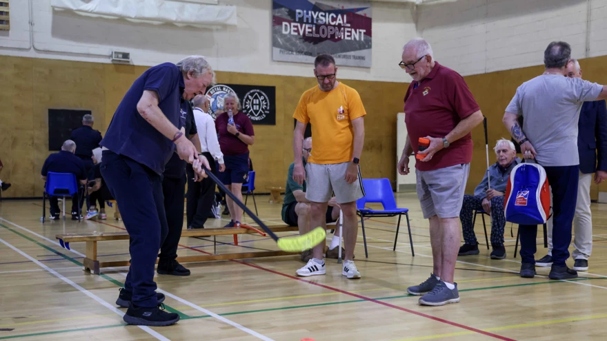 Two blind veterans partake in a hockey based activity with a guide
