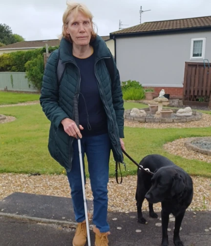 Blind veteran Jill standing with her cane and dog