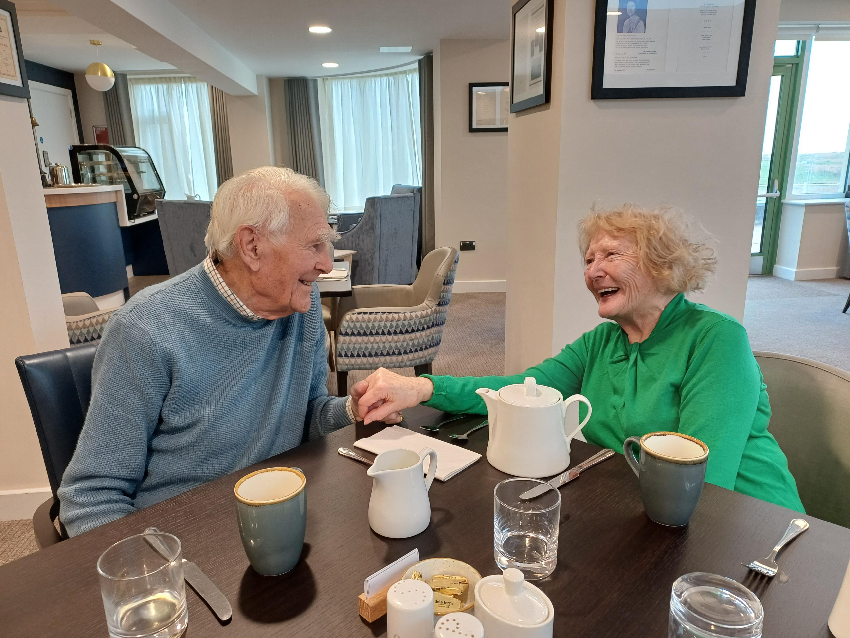 Blind veteran Patrick and his wife Jacky sit at a table at our Rustington Centre, holding hands and looking into each others eyes lovingly