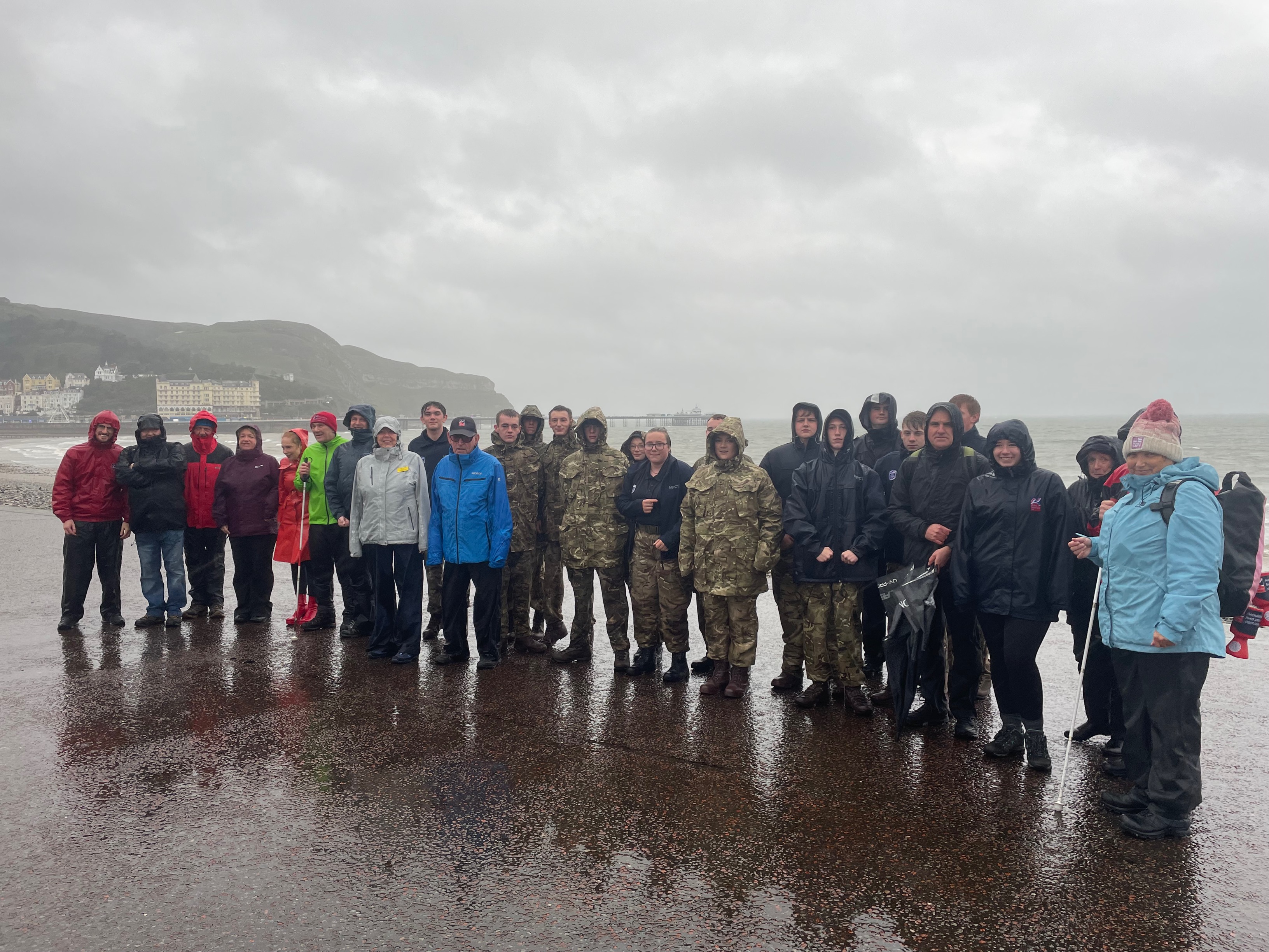 A group 26 students and staff stop for a photo as they make their way from our Llandudno Centre to the Llandudno War Memorial in very wet and windy conditions.