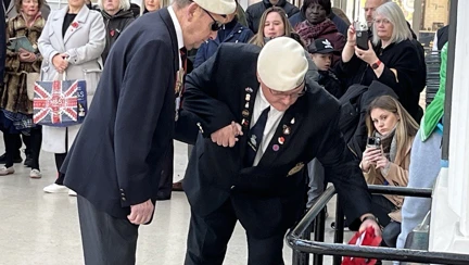 Tony is being assisted to place his wreath at the base of the War Memorial