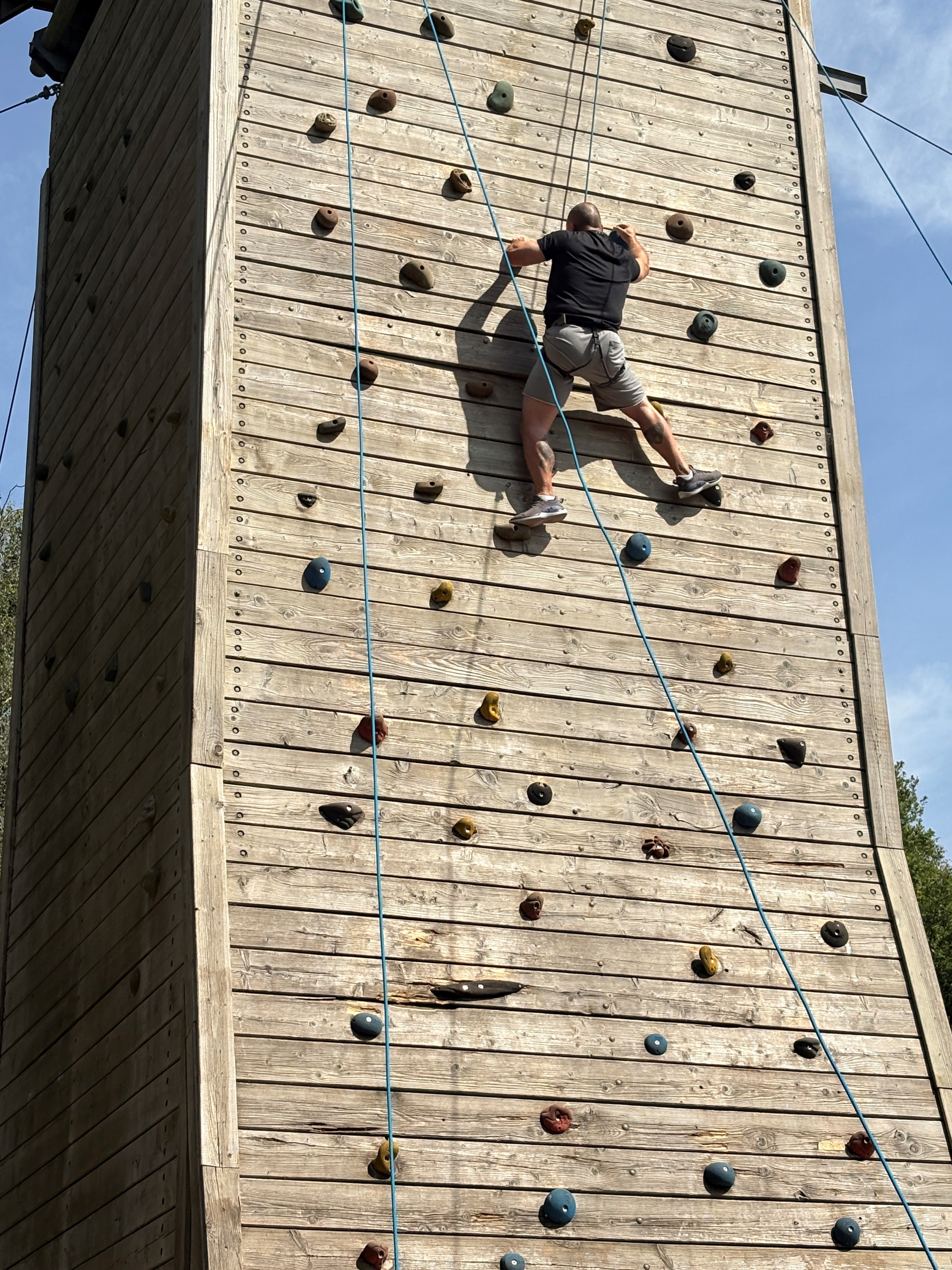 Stuart near the top of a wooden climbing wall