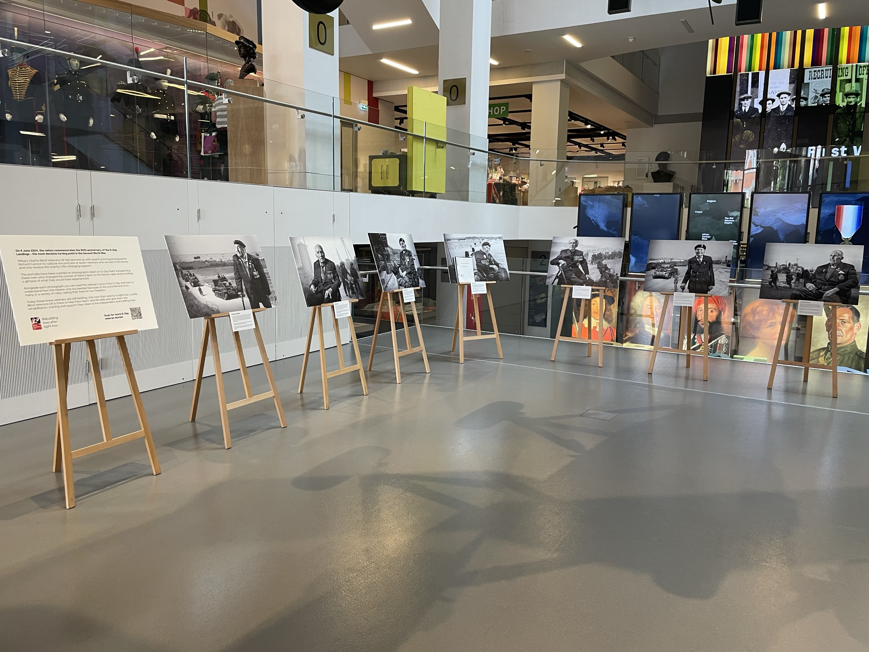 Seven black and white large canvas photographs displayed on easels in an exhibition space