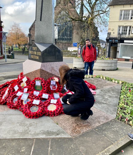 Stephanie knelt down placing a poppy wreath alongside others at a war memorial