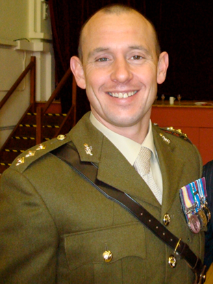 A head-shot of Justin, smiling in military uniform