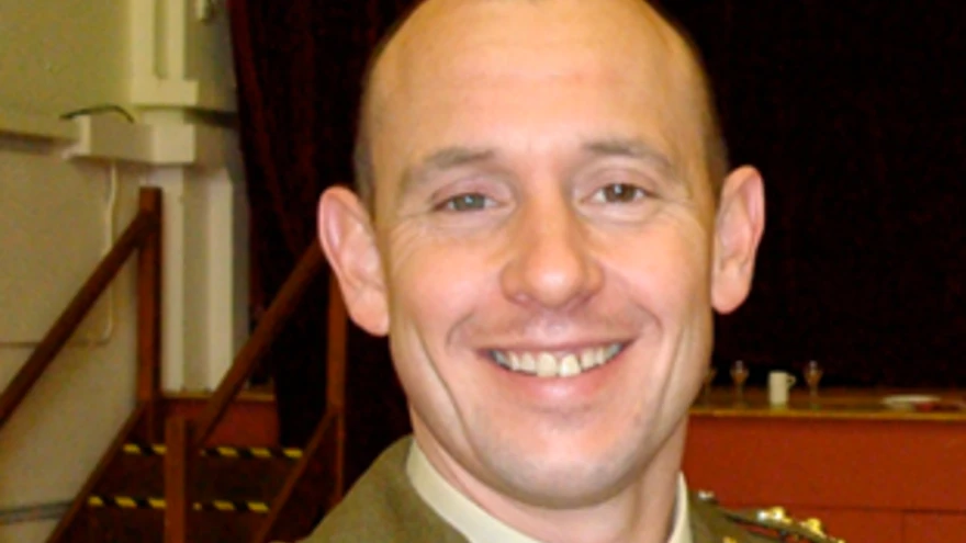 A head-shot of Justin, smiling in military uniform