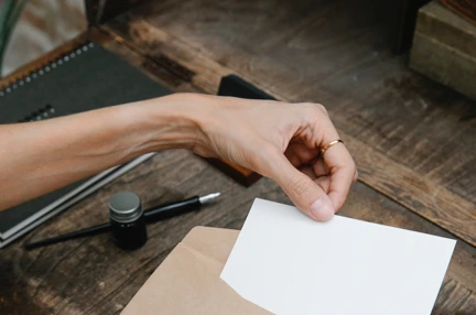 A woman's hands placing a small piece of paper into an envelope