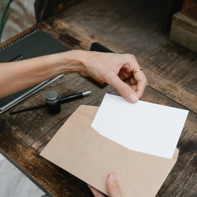 A woman's hands placing a small piece of paper into an envelope