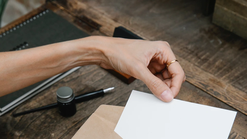 A woman's hands placing a small piece of paper into an envelope