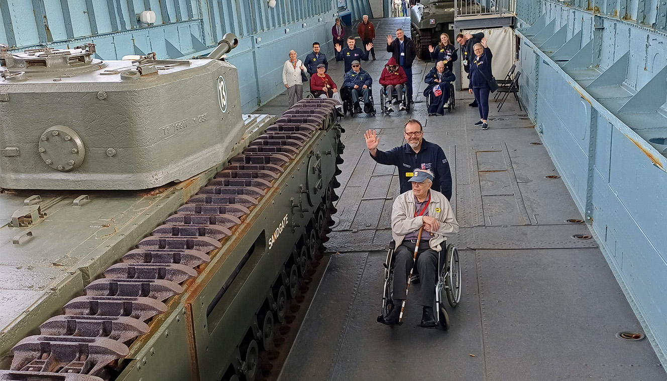 A photo of blind veterans looking at a D-Day museum landing craft