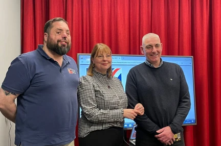 Blind veterans Simon and Kevin stood either side of a lady. All smiling at the camera
