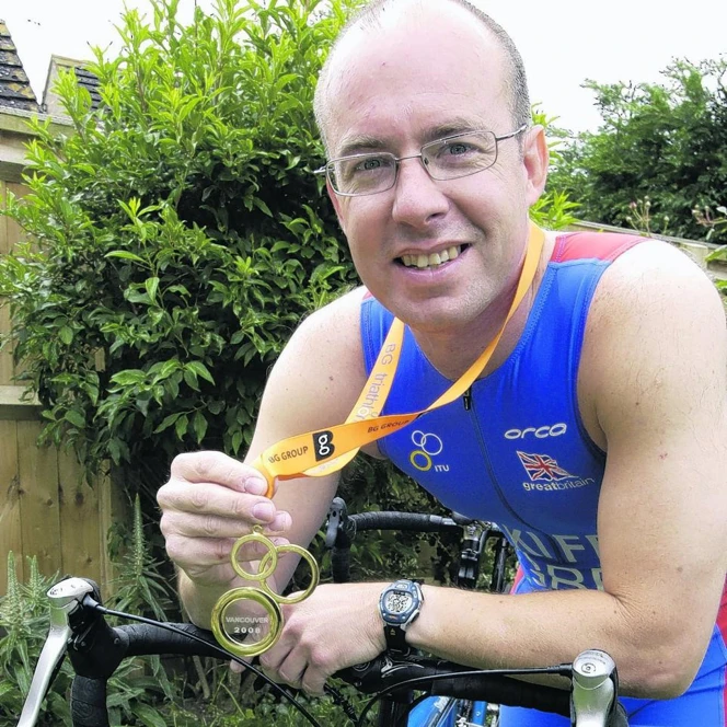 Graham outside, sitting on his bike and showing off his gold medal