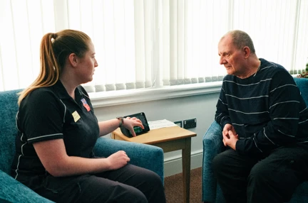 Rhian, a Wellbeing Specialist demonstrates the new Amazon Alexa at the Llandudno Centre to Blind Veteran Jules
