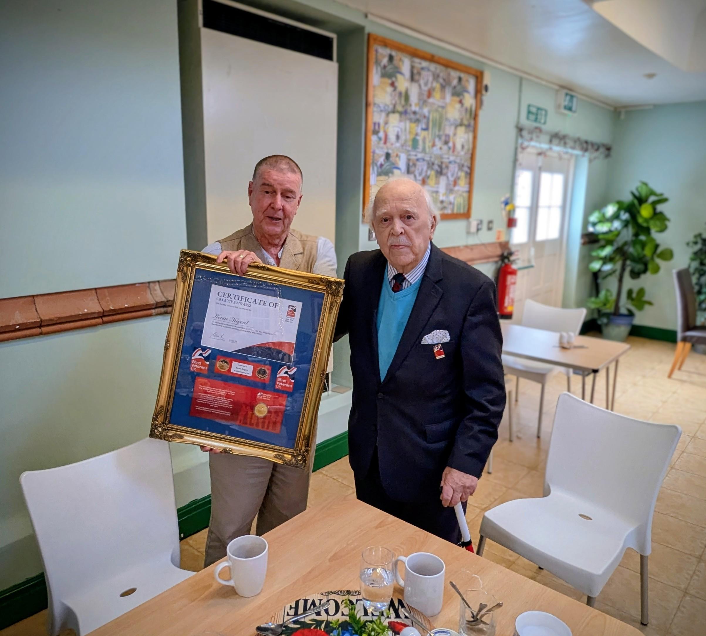 Brian and Kevin stand next to each other and Kevin holds his framed award