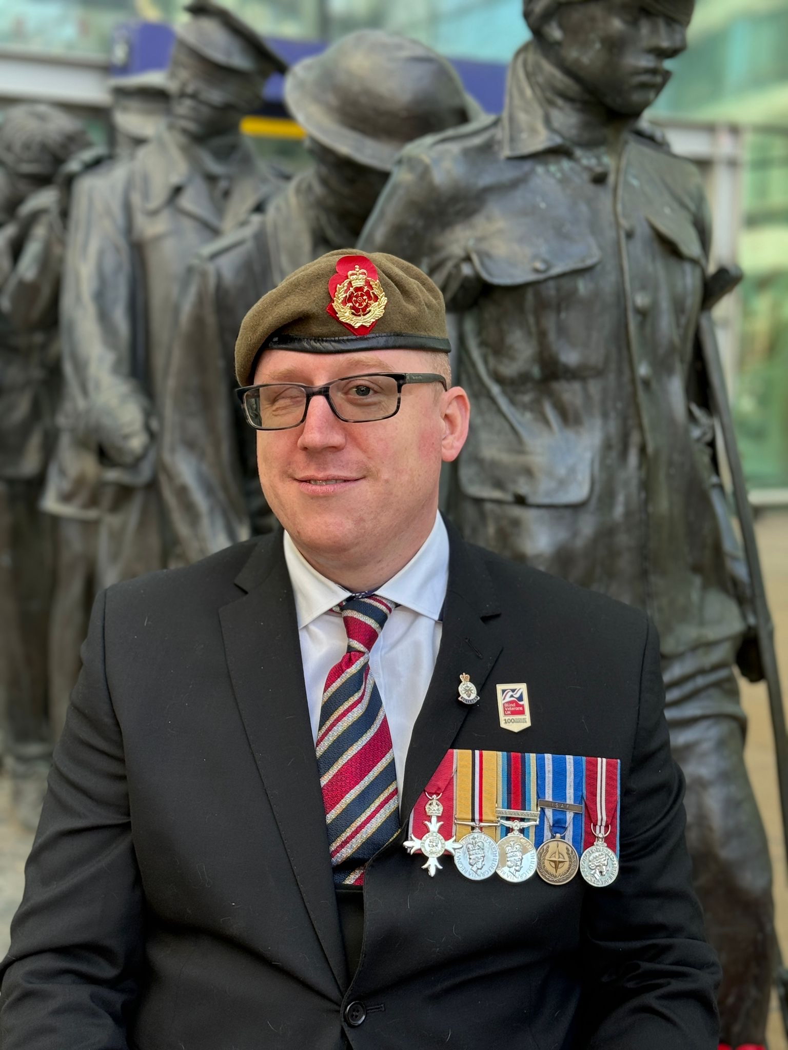 Coops sits in front of our Victory over Blindness statue, wearing his beret and medals
