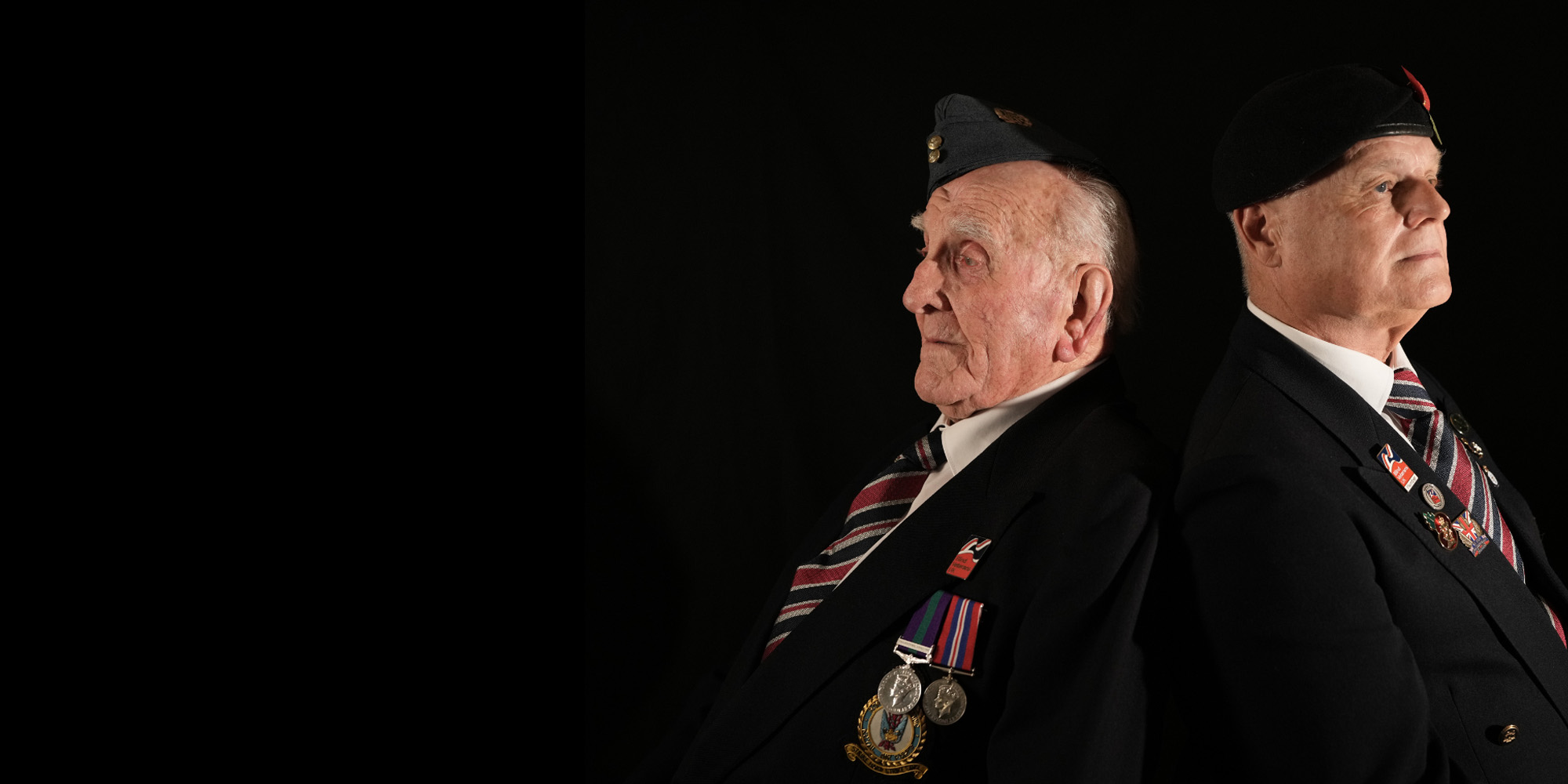 Blind veterans Michael and Wayne sat back to back with a black background