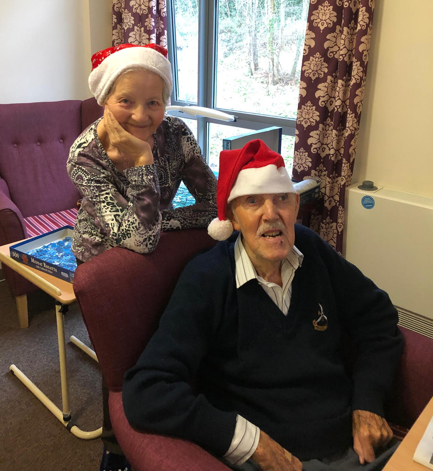 Blind veteran Bill and his wife, smiling and wearing Christmas hats