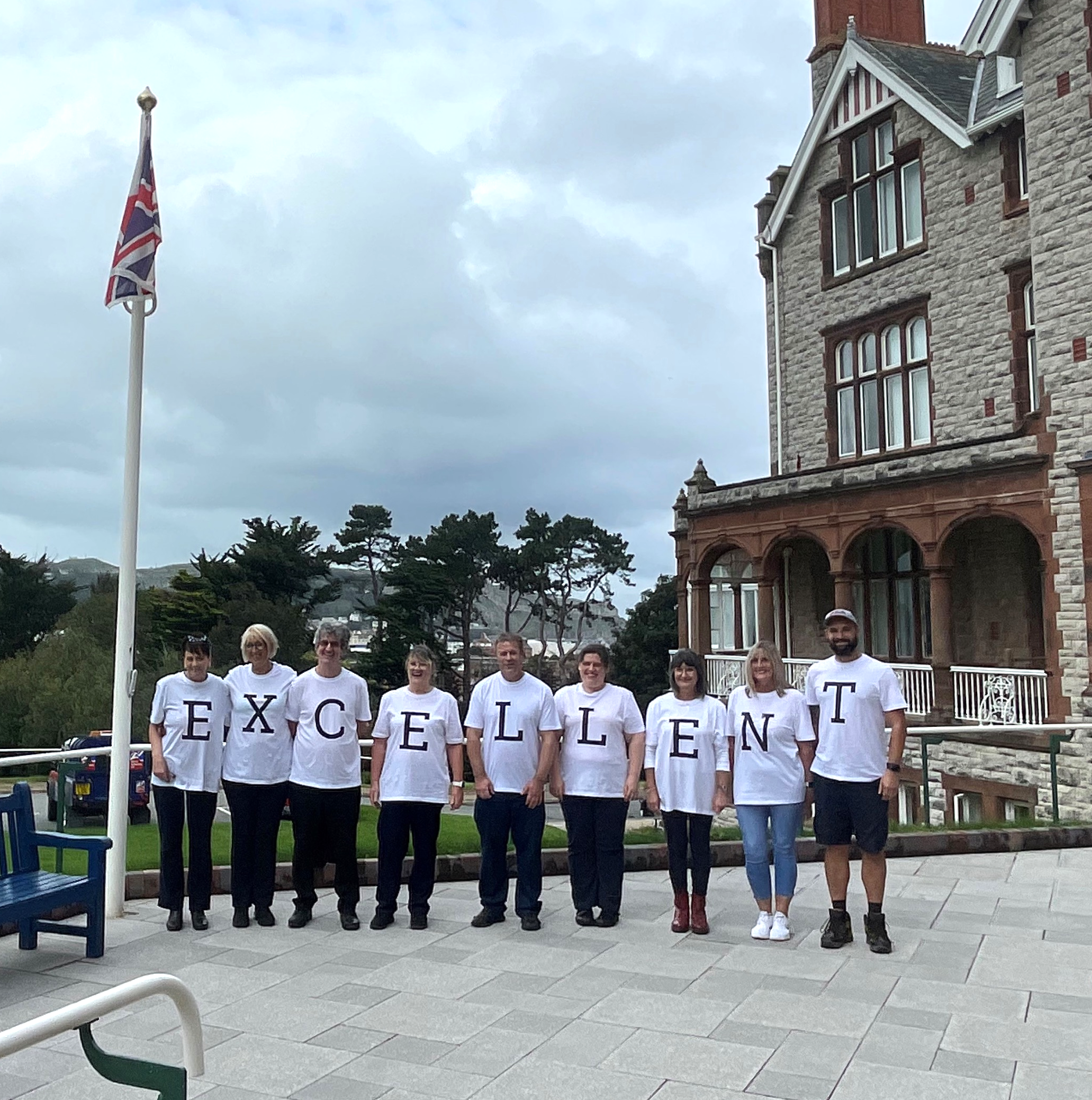 A group of nine Landudno Centre staff stood in front of the building wearing t-shirts with letters on which when all stood together spell "Excellent"