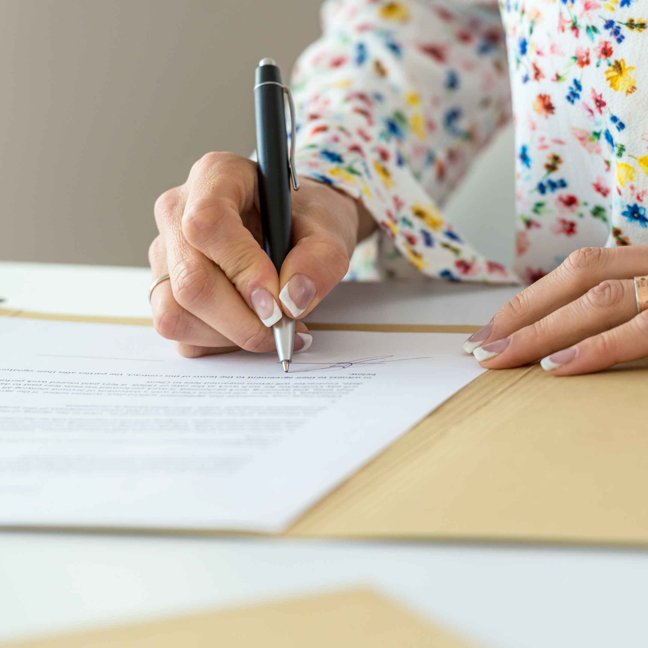 A woman sat at a desk using a pen to write on documents.