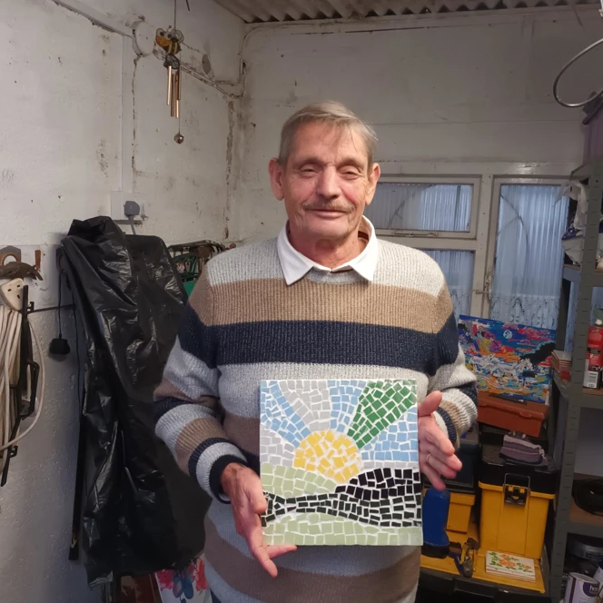Blind veteran Cameron, standing in his garage with a mosaic