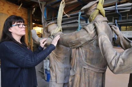 Artist Johanna Domke-Guyot placing her hands on the arms of the Victory Over Blindness statue