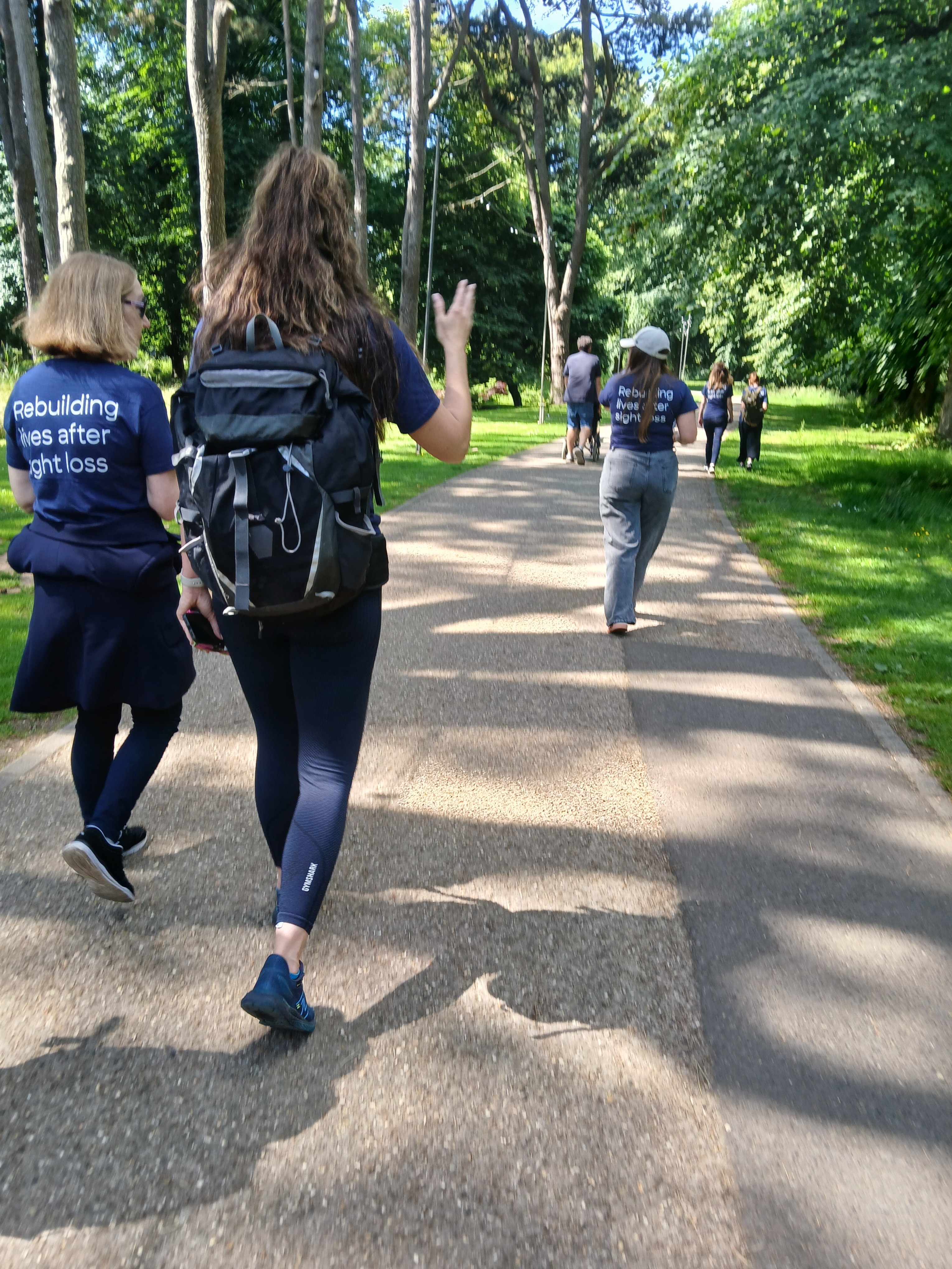 The group of volunteers walk together along a shaded pathway